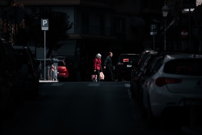 穿着红色夹克的男人在夜间站在黑色汽车旁边